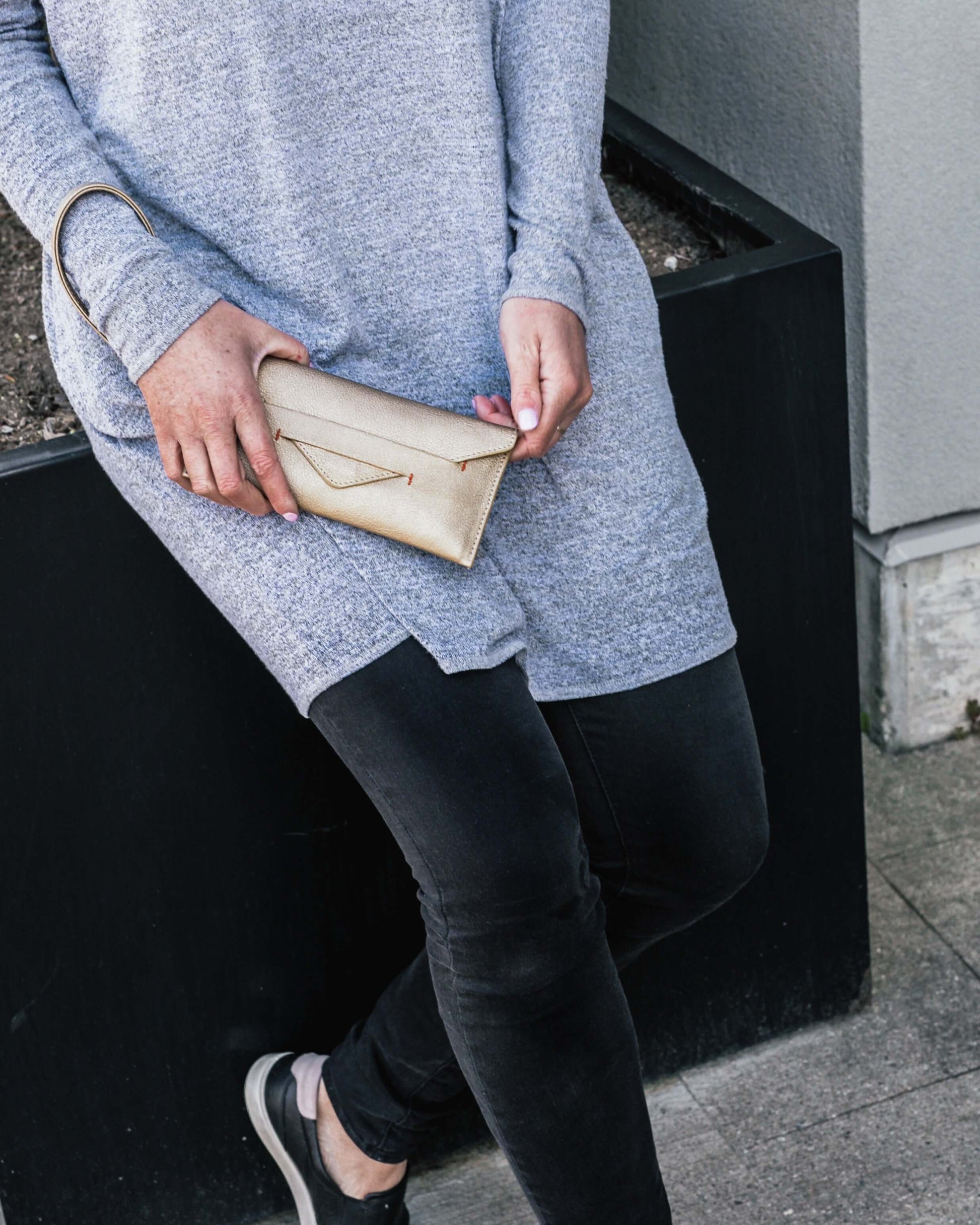 Woman holding Delancey Vegan Wallet in beige, showcasing detachable wrist strap and slim design.